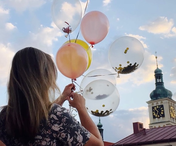 Frau mit Luftballons vor Kirchturm